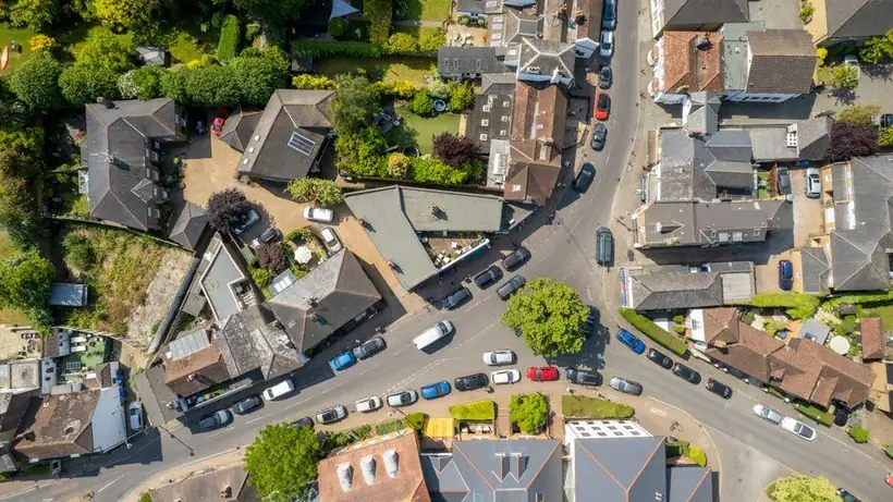 Aerial view over an English town of pitched roofs mixed with flat-roofed garages, extensions and outbuildings, like the estates behind Burnham-on-Sea and Highbridge
