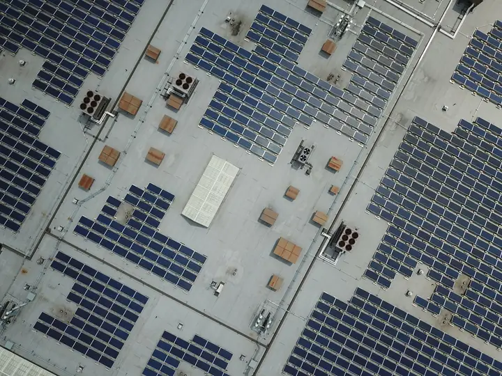 Rows of tilted solar panels ballasted on a large flat roof with spacing between rows to avoid self-shading
