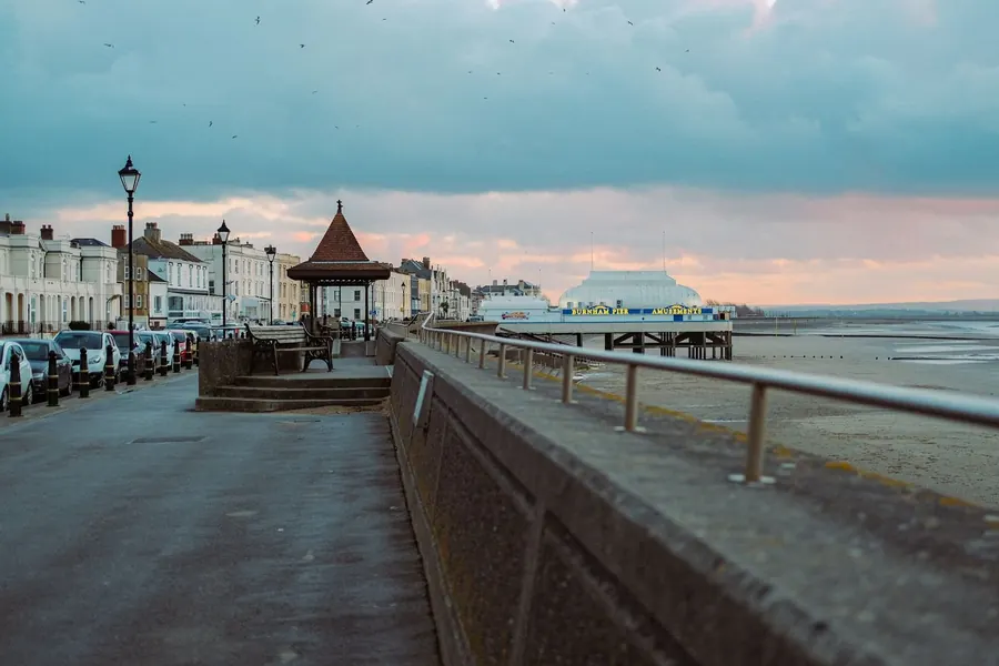 A promenade and pier on the Bristol Channel under a south-westerly sky, the same weather that drives rain at west-facing roof junctions in Weston-super-Mare