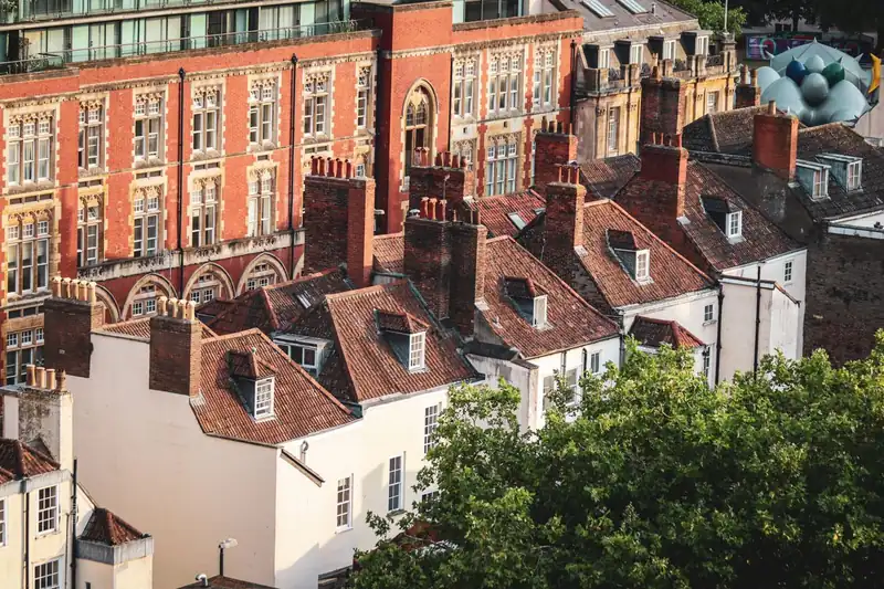 Rendered West Country terraces with brick chimney stacks rising through clay tile roofs, the stacks flashed where they meet the roof in the same way a flat roof upstand meets the house wall