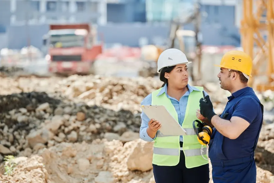 Two roofers comparing job details on site before pricing a flat roof in Weston-super-Mare