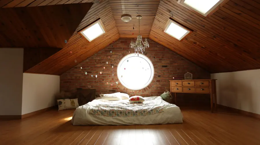 A converted loft bedroom with timber-lined sloping ceilings and rooflights, the kind of room where dormer roof leaks show up first