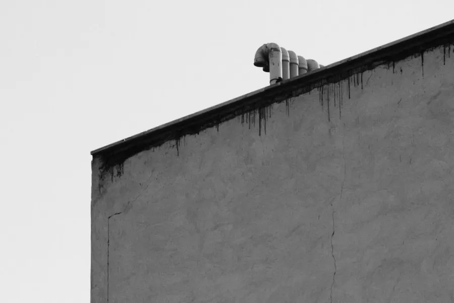 The edge and parapet detail of a flat roof, where the total build-up height becomes visible on an extension