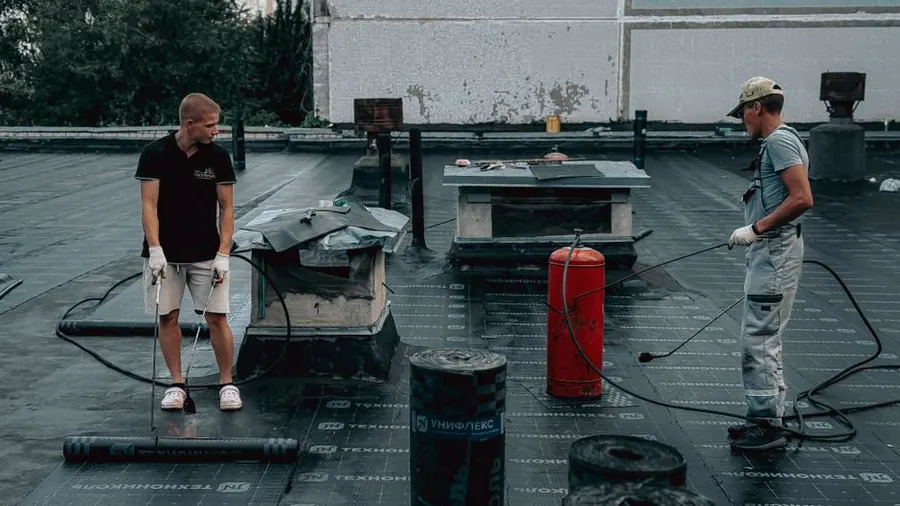 A liquid waterproofing system being worked across a flat roof, the process sold as a roof coating in Weston-super-Mare