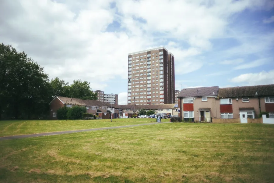 A postwar British housing estate with tower block and low-rise homes, the era that built flat roofs by the thousand
