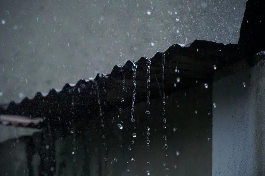 Rain pouring off a roof edge during the kind of shower that stops flat roofing work in Weston-super-Mare