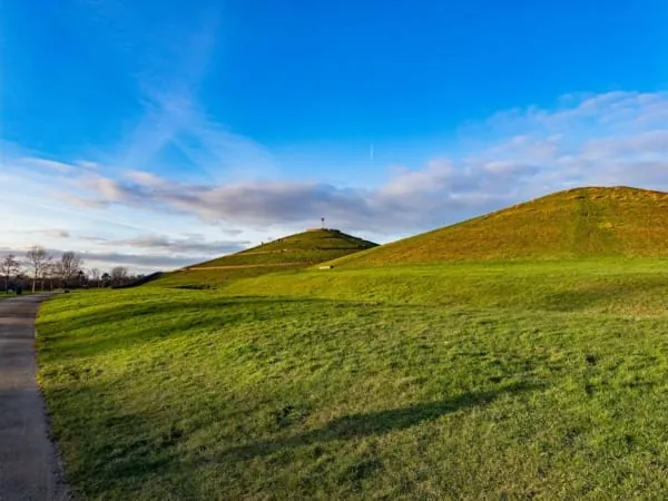 A grassy earthwork mound on parkland, the kind of Norman motte preserved at Castle Batch in Worle