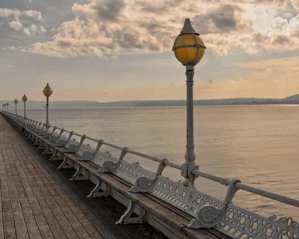 Victorian lamps and benches along a pier's decking, the promenade Clevedon Pier gives its walkers
