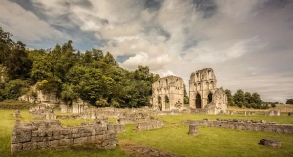 Ruined monastic walls in green parkland, the kind of remains Glastonbury Abbey keeps at the heart of town