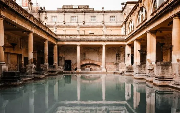 The steaming green water and stone columns of the Roman Baths at the heart of Bath