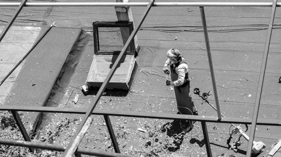 A roofer working across a stripped flat roof deck during a replacement in Weston-super-Mare