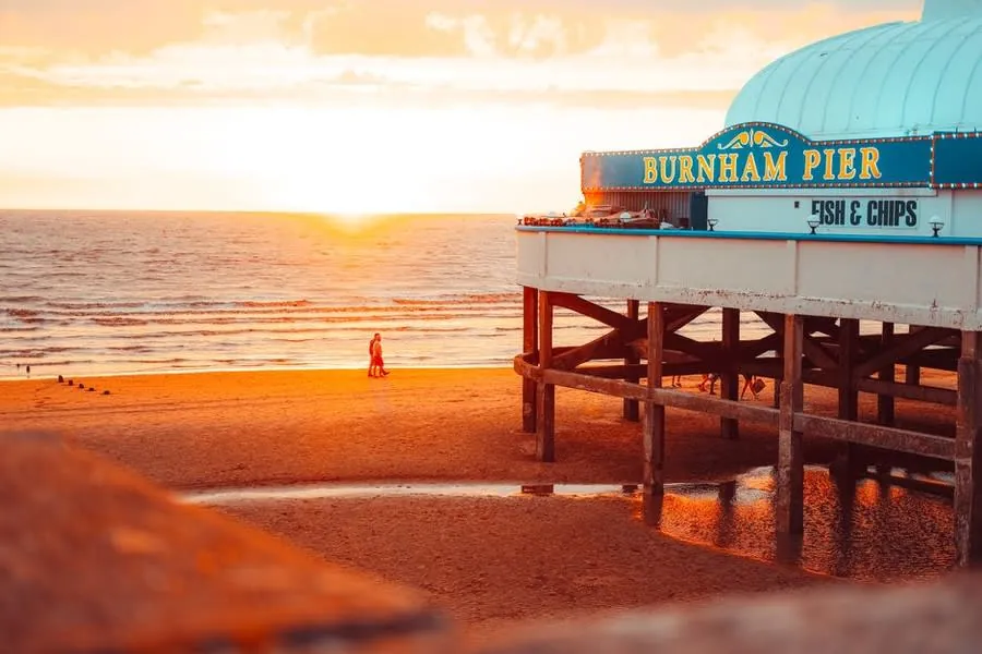 Burnham-on-Sea's small pier pavilion on the sands at sunset, the seafront that the town's older flat roofs face