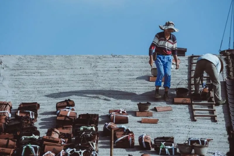 Roofer working on a felt flat roof covering, with materials laid out on the deck